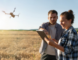 Two people operating a drone above a field.